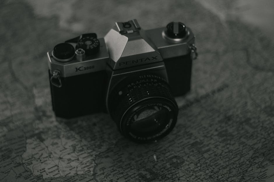 Close-up of a Pentax K1000 camera on a vintage map, evoking nostalgia.